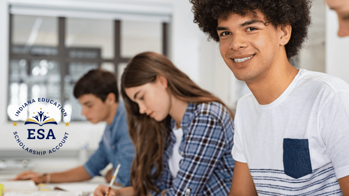 A smiling student sits at a desk in a classroom with two classmates writing beside him. The Indiana Education Scholarship Account (ESA) logo and the CHOOSE Act Alabama emblem are displayed on the left side of the image.