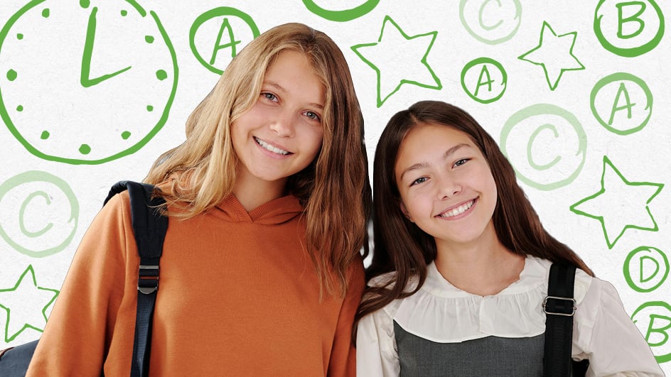 Older student and younger student stand together smiling
