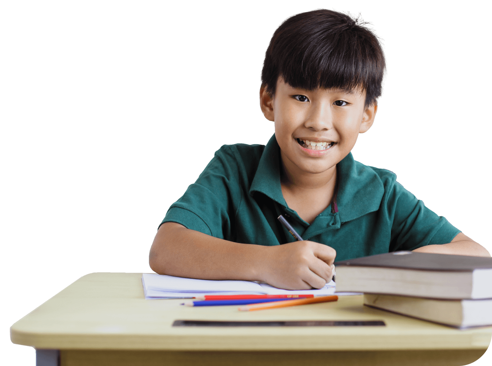 Cheerful boy in a green shirt writing in a notebook at a desk